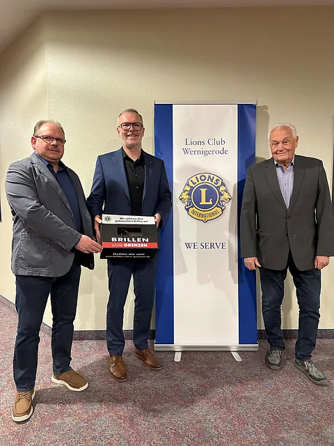 Spendenübergabe, 3 Männer vor Lions-Club Banner